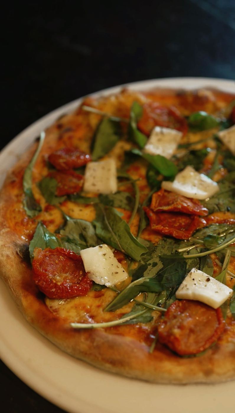 Pizza com rúcula, tomate seco e queijo